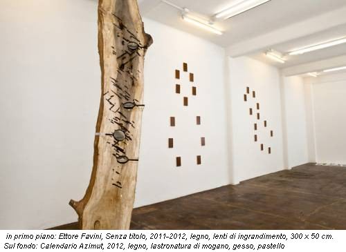 in primo piano: Ettore Favini, Senza titolo, 2011-2012, legno, lenti di ingrandimento, 300 x 50 cm. Sul fondo: Calendario Azimut, 2012, legno, lastronatura di mogano, gesso, pastello