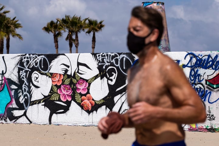 Una delle notizie dal mondo dell'arte di questa settimana è la racconta di street art a tema Coronavirus. Qui un'opera sul muro di una spiaggia a Los Angeles (Photograph: Étienne Laurent/EPA)