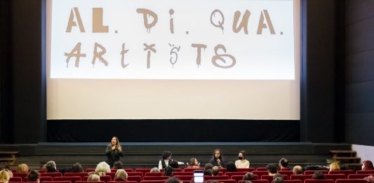 Al.Di.Qua Artists, la prima associazione di e per le persone con disabilità nello spettacolo Il cinema Nuovo Sacher di Roma nel corso della presentazione del Video Manifesto dell'associazione Al.Di.Qua Artists. Sullo schermo, il logo dell'associazione (Ph: Annamaria Benedetto).