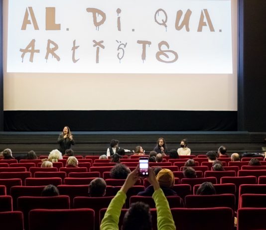 Al.Di.Qua Artists, la prima associazione di e per le persone con disabilità nello spettacolo Il cinema Nuovo Sacher di Roma nel corso della presentazione del Video Manifesto dell'associazione Al.Di.Qua Artists. Sullo schermo, il logo dell'associazione (Ph: Annamaria Benedetto).
